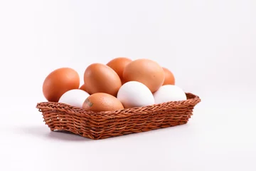 Foto auf Leinwand Brown and white chicken eggs lying in a wicker basket. © milanchikov