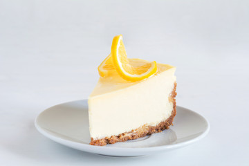 Slice of Lemon Cheesecake on white plate on gray background