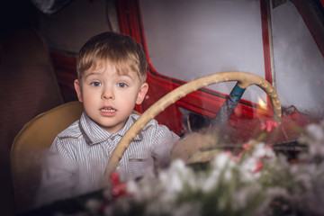 Маленький мальчик сидит за рулем машины 