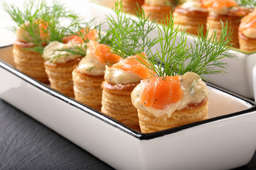 Appetizer puff pastry with dill dip and salmon on stone tray