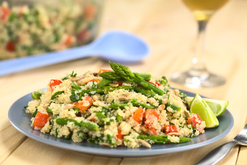 Vegetarian quinoa dish with green asparagus and red bell pepper, sprinkled with parsley and roasted...