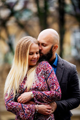 Fototapeta premium Young couple in love, hugging on the street. Selective focus. bald guy with a beard