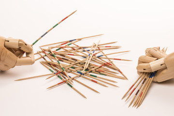 Wooden hands play game of mikado on white background