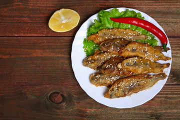 closeup of a plate with spanish boquerones fritos, battered and fried anchovies typical in Spain, on a rustic wooden table