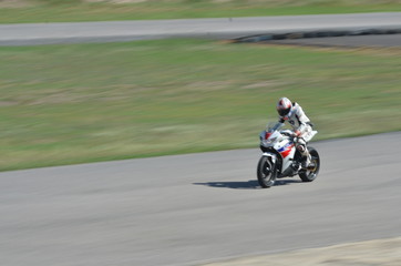 Fototapeta premium Zamazani sportowcy ćwiczący motocykle wyścigowe na torze wyścigowym