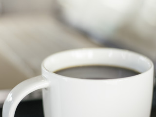 Mug of black coffee with computer bokeh