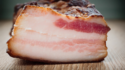Fresh homemade smoked bacon on a wooden plate
