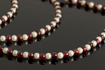 Closeup beads from garnet crystal and pink pearls on black 