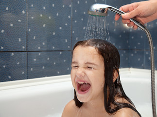 mom pours a little girl out of the shower