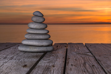 Stacked pebbles on a wooden surface and setting sun