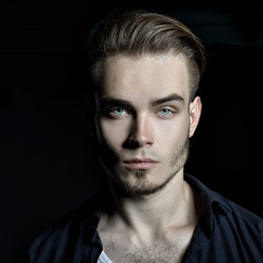 Obraz premium Portrait of young man over black background, image toned.