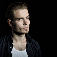 Portrait of young man, studio shot over black background, image