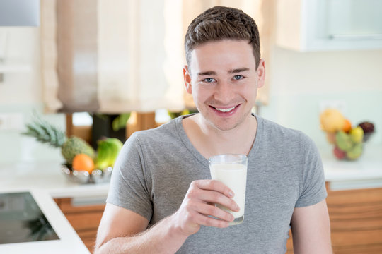 Happy smiling Man in his Kitchen, enjoying a glass of Milk
