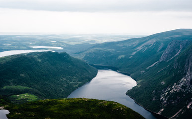 Inland fjord between steep cliffs against green landscape