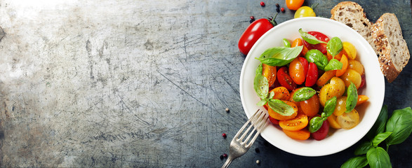 Fresh tomatoes with basil leaves in a bowl