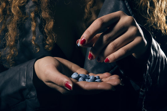 Drug abuse. Woman with pills in hand taking one.