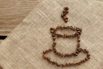 Cup of coffee beans on linen top view
