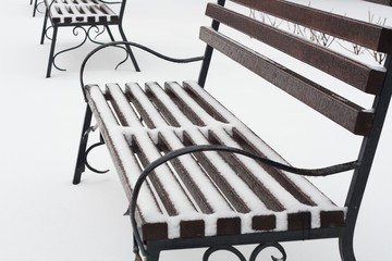 bench on the street in snow. bench from a tree and metal. on white snow on the street park