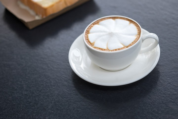 Hot art latte coffee in cup on black table