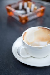 .Empty coffee cup after drink with cigarette butt on wood table