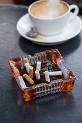 Empty coffee cup after drink with cigarette butt on wood table