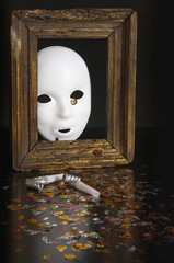 White mask in an old frame on a black background