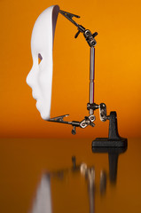 Iron alligator clip stand with white mask on an orange background