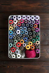 Spools of threads on the wood background