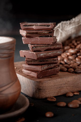 Fresh roasted coffee beans and stack of brown chocolate.