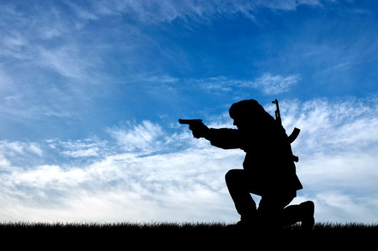 Silhouette of man with gun against cloudy sky