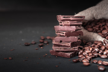 Fresh roasted coffee beans and stack of brown chocolate.