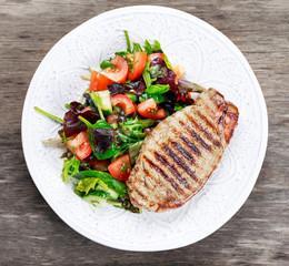 Grilled pork meat and vegetables on plate