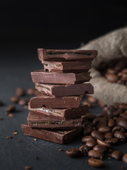 Fresh roasted coffee beans and stack of brown chocolate.