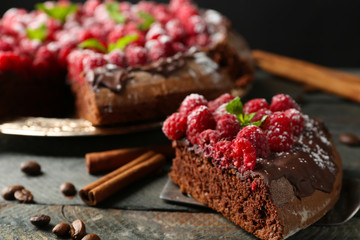 Piece of cake with chocolate Glaze and raspberries on color wooden background