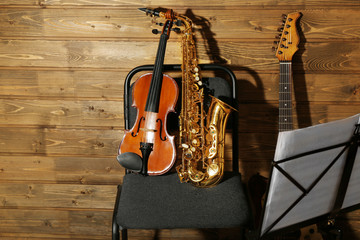 Naklejka premium Musical instruments on a chair and note holder against wooden background