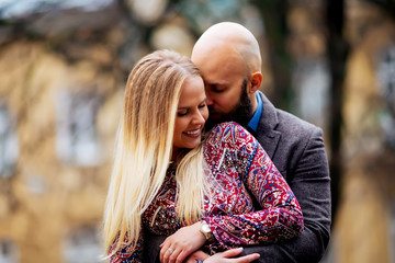 Fototapeta premium Young couple in love, hugging on the street. Selective focus. bald guy with a beard