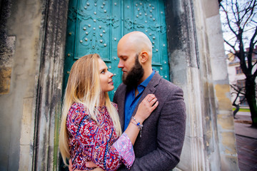 One beautiful stylish couple of young woman and senior man with long black beard sitting embracing close to each other outdoor in autumn street on stairs sunny day, horizontal picture