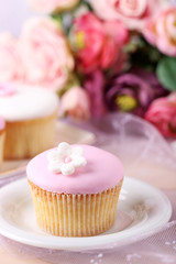 Tasty cupcake on saucer, on light background