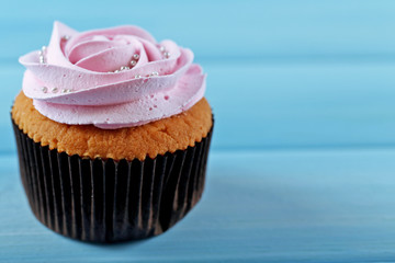 Tasty cupcake on color wooden background