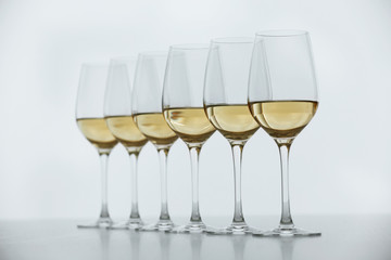 Wineglasses with white wine on wooden table on bright background