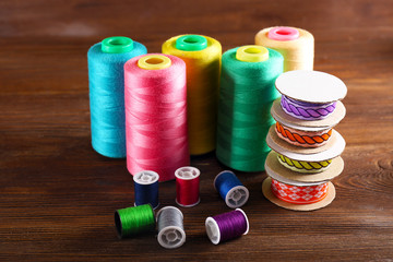 Spools of color ribbon and thread on wooden background