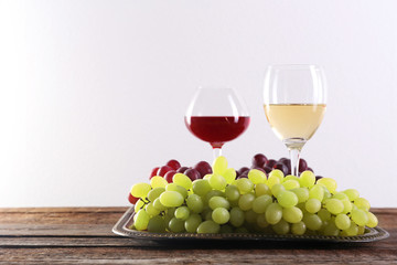 Wine and grape on wooden table against light background