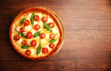 Pizza Margherita with arugula on wooden background