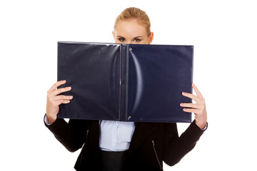 Business woman hiding face behind binder