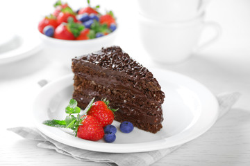 Fototapeta na wymiar Chocolate cake with chocolate cream and fresh berries on plate, on light background