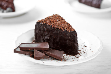 Chocolate cake with chocolate cream on plate, on light background