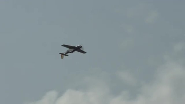 North American P-51 Mustang fighter plane passes from left, rolls into an inverted position.  Recorded in 4K, ultra high definition.