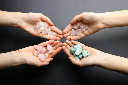 Women holding semiprecious stones in their hands on dark grey background