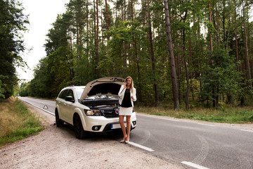 Fototapeta premium Young woman with broken car calling for help