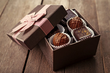 Delicious chocolate candies in beautiful gift box on wooden background